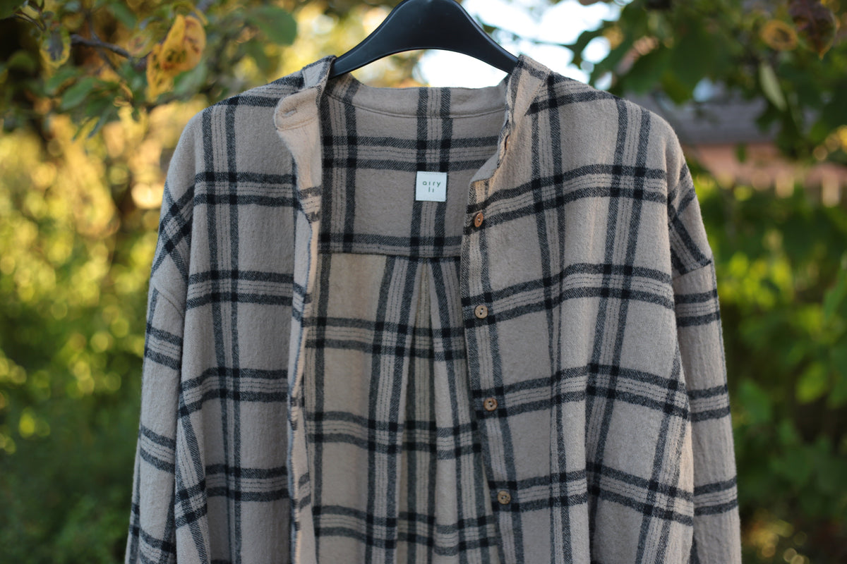 Plaid shirt on a hanger with a blurred natural background